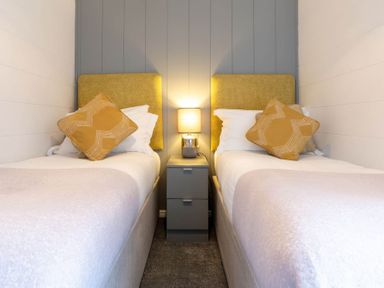 A bedroom with two beds and a lamp on a nightstand at The Falls (Pet) Leyburn
