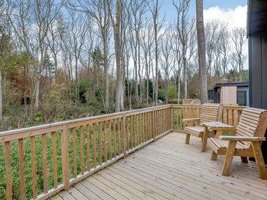 An outdoor deck with wooden chairs overlooking trees at Tennyson Spa in Louth
