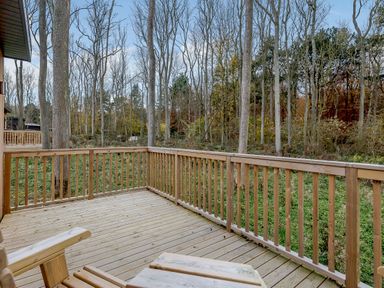 A wooden deck with railings and trees in the background at Tennyson Spa in Louth