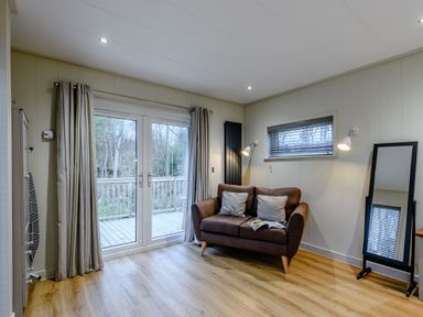 A living room with a sofa and sliding door at Tennyson Spa (Pet) in Louth