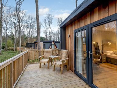 A patio with wooden chairs and a table at Tennyson Spa (Pet) Louth