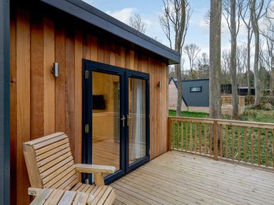 An outdoor space with a wooden deck and a glass door at Tennyson Spa (Pet) in Louth