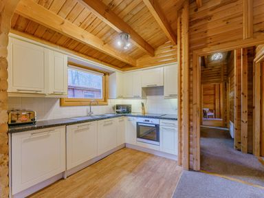 A kitchen with cabinets and a window at Maple Lodge in Louth