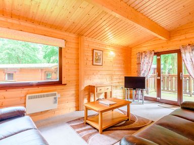 A living room with wooden walls and a coffee table at Maple Lodge in Louth