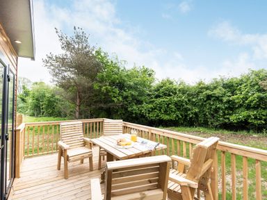 A deck with wooden furniture and greenery at Caistor Spa in Louth