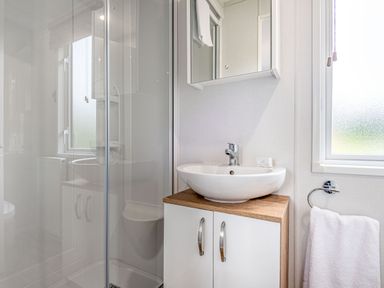 A bathroom with a shower, sink, and mirror at Caistor Spa in Louth