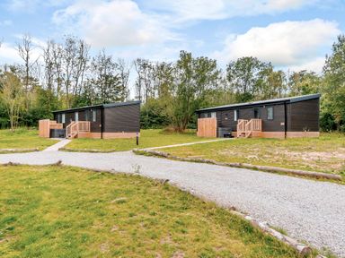 Two cabins with a pathway in a wooded area at Horncastle Plus in Louth