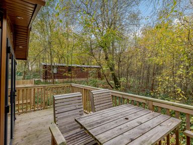 A deck with a table and chairs surrounded by trees at Alford Spa in Louth