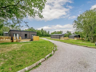 An outdoor area with wooden lodges and a gravel path at Horncastle Spa Plus in Louth