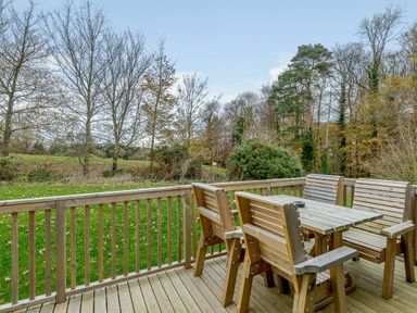 An outdoor deck with wooden furniture overlooking a grassy area at The Kinder Spa (Pet) Louth