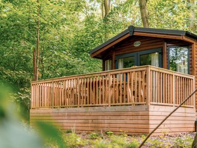 A cabin with a wooden deck and outdoor seating at Alford Spa (Pet) Louth