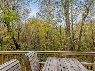 An outdoor area with a wooden table and chairs overlooking trees at Alford Spa (Pet) Louth