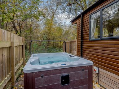 A hot tub beside a wooden cabin in a garden at Alford Spa (Pet) Louth