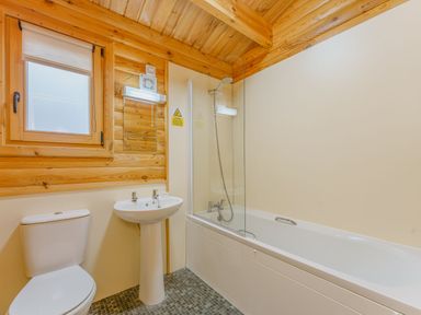 A bathroom with a toilet, sink, bathtub, and shower at Cedar Lodge in Louth