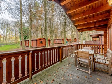 An outdoor deck area with a wooden table and chairs at Cedar Lodge in Louth