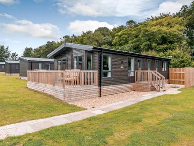 A log cabin with a deck and pathway at Elsham Lodge in Louth