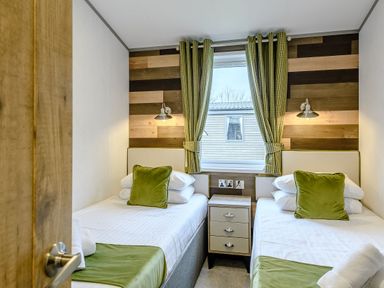 A bedroom with two beds and a nightstand at Elsham Lodge in Louth