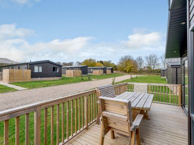 An outdoor area with a table and seating overlooking lodges at Elsham Lodge in Louth