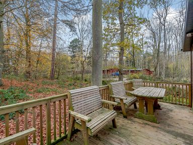 A deck with chairs and a table surrounded by trees at Stamford Spa (Pet) Louth