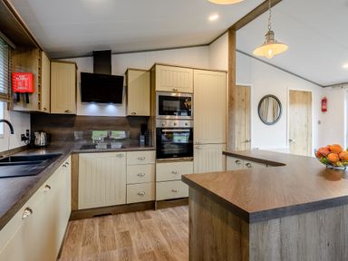 A kitchen with cabinets, stove, sink, and a fruit bowl at Elsham Lodge (Pet) in Louth