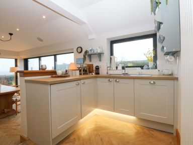 A kitchen with cabinets and a sink at Bryn Mor Cottage in Mynytho near Llanbedrog