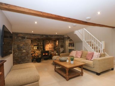 A living room with a sofa, coffee table and fireplace at Bryn Mor Cottage in Mynytho near Llanbedrog
