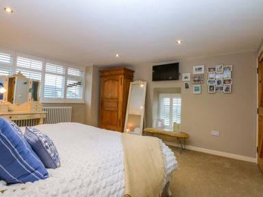 A bedroom with a bed and dresser at Bryn Mor Cottage in Mynytho near Llanbedrog