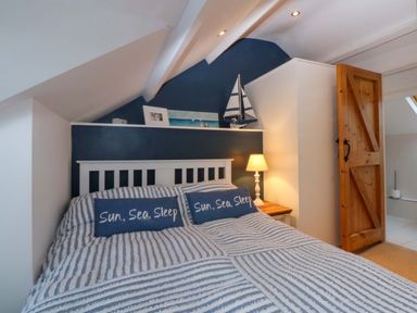 A bedroom with a bed and decorative items at Bryn Mor Cottage in Mynytho near Llanbedrog