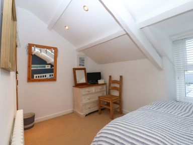 A bedroom with a chair and a dresser at Bryn Mor Cottage, Mynytho near Llanbedrog