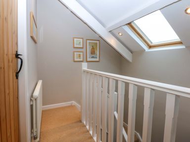 A hallway with a staircase and stair railing at Bryn Mor Cottage in Mynytho near Llanbedrog