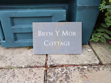 A sign with Bryn Y Mor Cottage on it near a garden in Mynytho near Llanbedrog