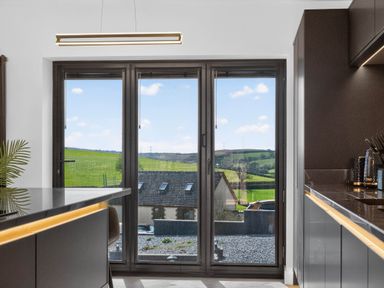 A kitchen with a window overlooking the countryside at Heddfan in Carmarthen