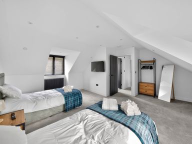 A bedroom with two beds and a wardrobe at Heddfan in Carmarthen