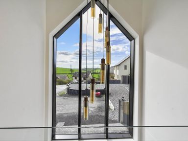 A window with light fixtures showing an outdoor view at Heddfan in Carmarthen