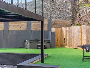 A garden with a hot tub and grill at Heddfan in Carmarthen