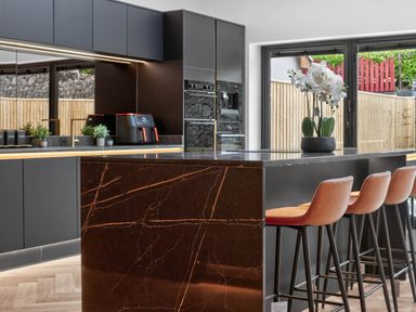 A kitchen with a dining area featuring a bar island and stools at Ty Uchel 