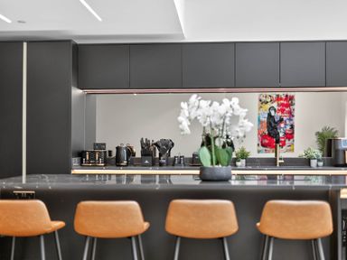A kitchen with a countertop, bar stools, and kitchen appliances at Ty Uchel