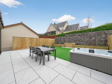 A garden with a table and chairs and a hot tub at Ty Uchel in 