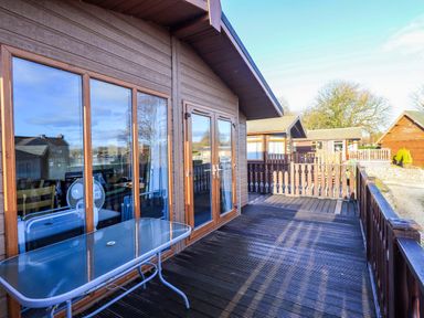 An outdoor deck with a table and chairs at Kingfisher Lodge