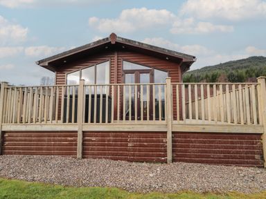 A wooden cabin with decking and railings at Monach 1