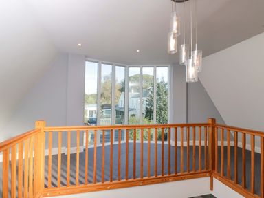 A landing area with a wooden railing and large windows at Lady Of Lourdes in Whitchurch, Herefordshire
