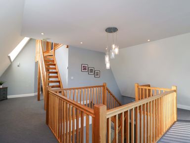 A hallway with staircase and framed pictures at Lady Of Lourdes in Whitchurch, Herefordshire