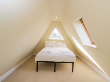 A bedroom with a bed and windows at Lady Of Lourdes in Whitchurch, Herefordshire