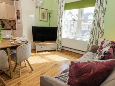 A living room with a tv and dining table at Rodwell Holt in Weymouth