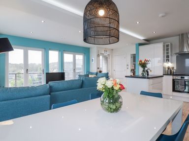 A living room with a sofa and flowers on a table at Adelaide in Portreath