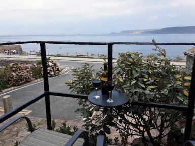 A balcony with wine glasses and a bottle overlooking the sea at Cove Retreat in Sennen Cove