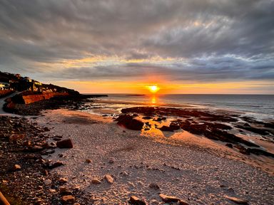 A scenic view of a sunset over the ocean at Cove Retreat in Sennen Cove