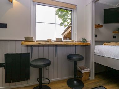 A kitchen with bar stools and counter at Little Hut in Grange-Over-Sands