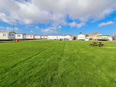 An outdoor area with grass and caravans at St Michaels Caravan Park - 236 Towyn