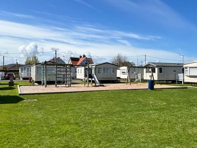 An outdoor area with playground equipment and caravans at The Beachside Hideout - St Michaels and Browns Caravan Park in Towyn